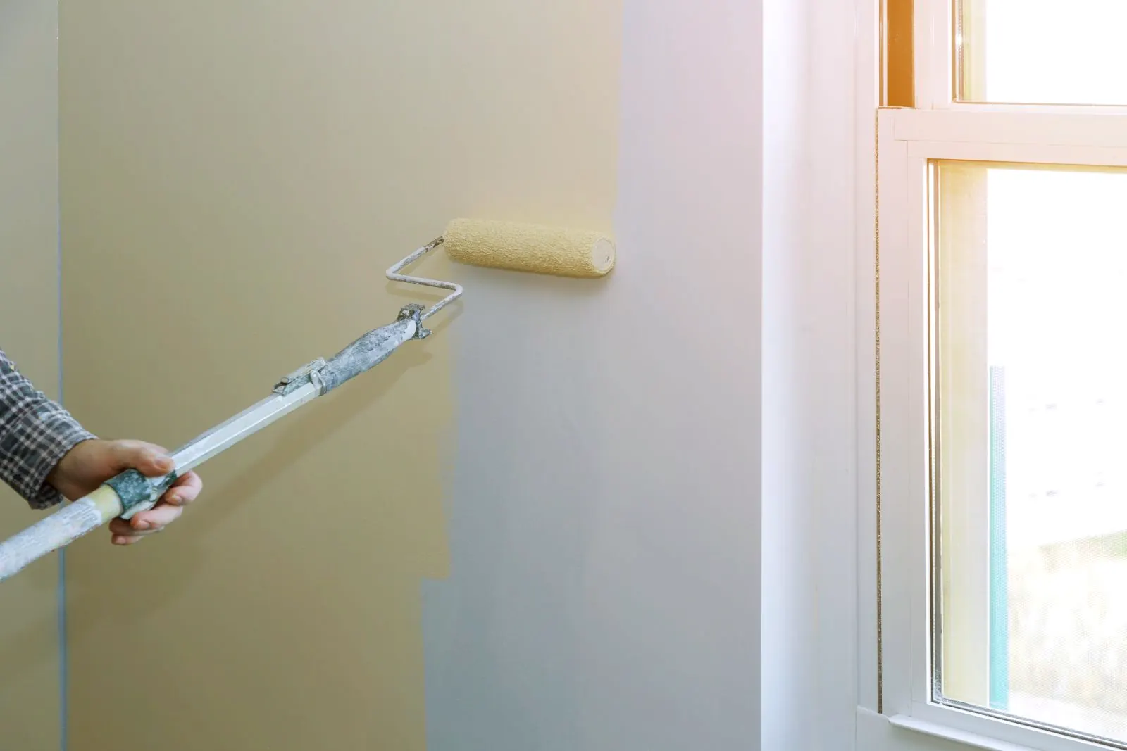 Rodillo pintando la pared de una vivienda en Pamplona