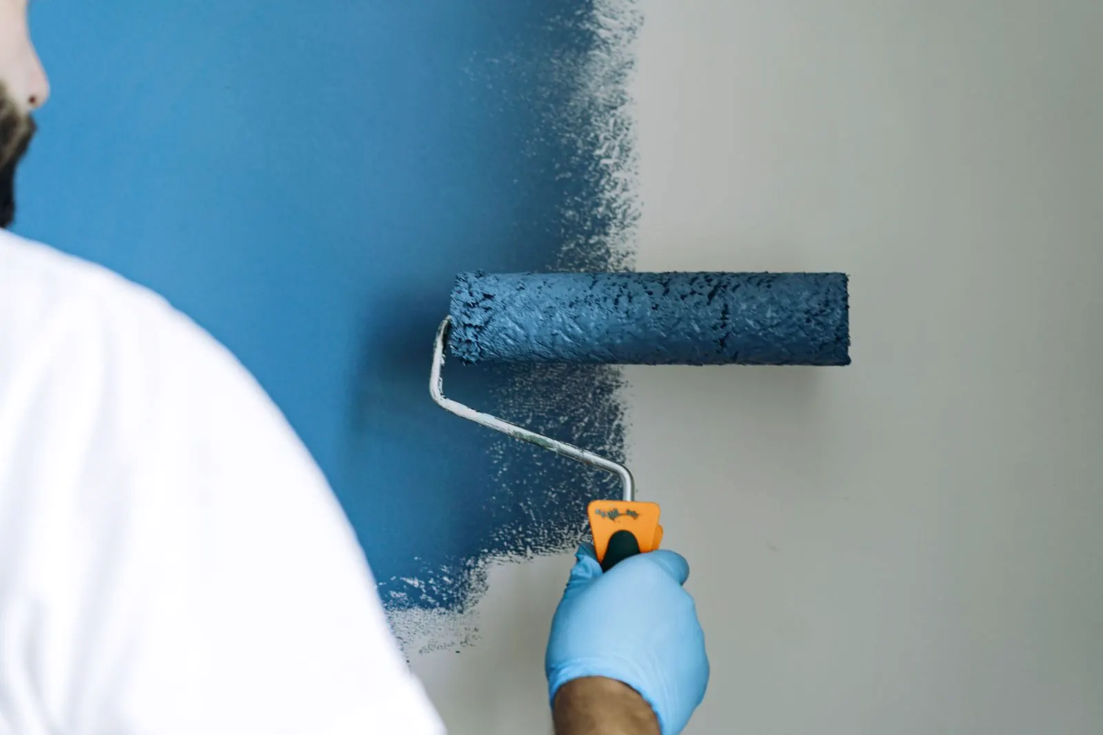 Rodillo aplicando pintura azul en la pared de una vivienda de Pamplona